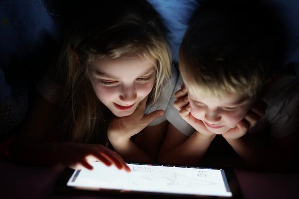 Siblings on tablet at night time